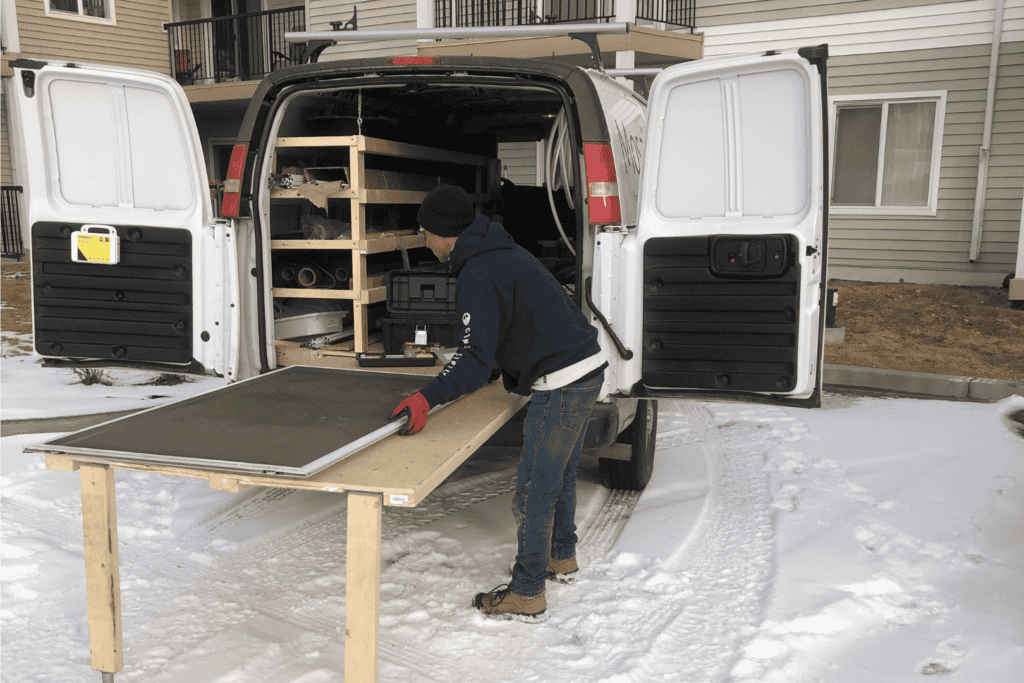 A Screen Savers Plus technician repairing a retractable screen door on a mobile workstation.